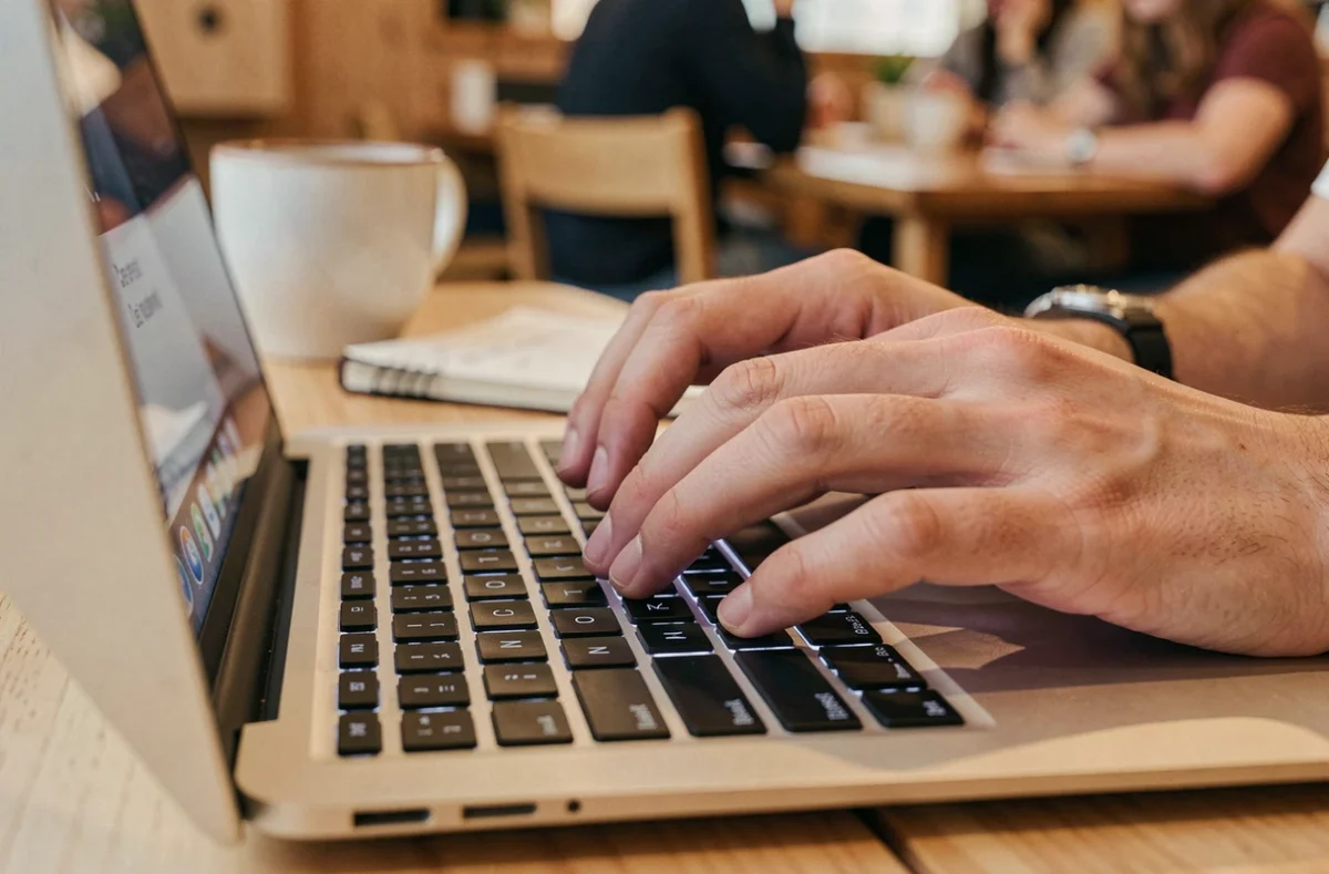 Gros plan sur des mains tapant une combinaison de touches pour écrire le Ç majuscule sur un clavier d'ordinateur portable